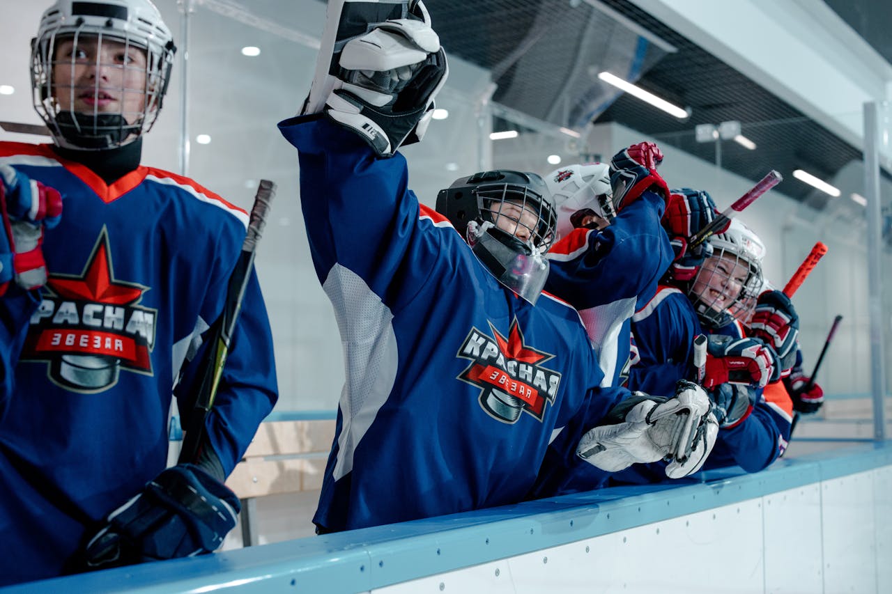 Group of ice hockey players in blue jerseys celebrating a win indoors.