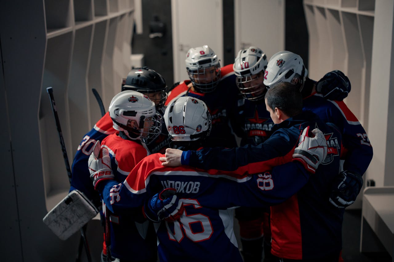 Team of young hockey players in locker room huddle, building team spirit before game.