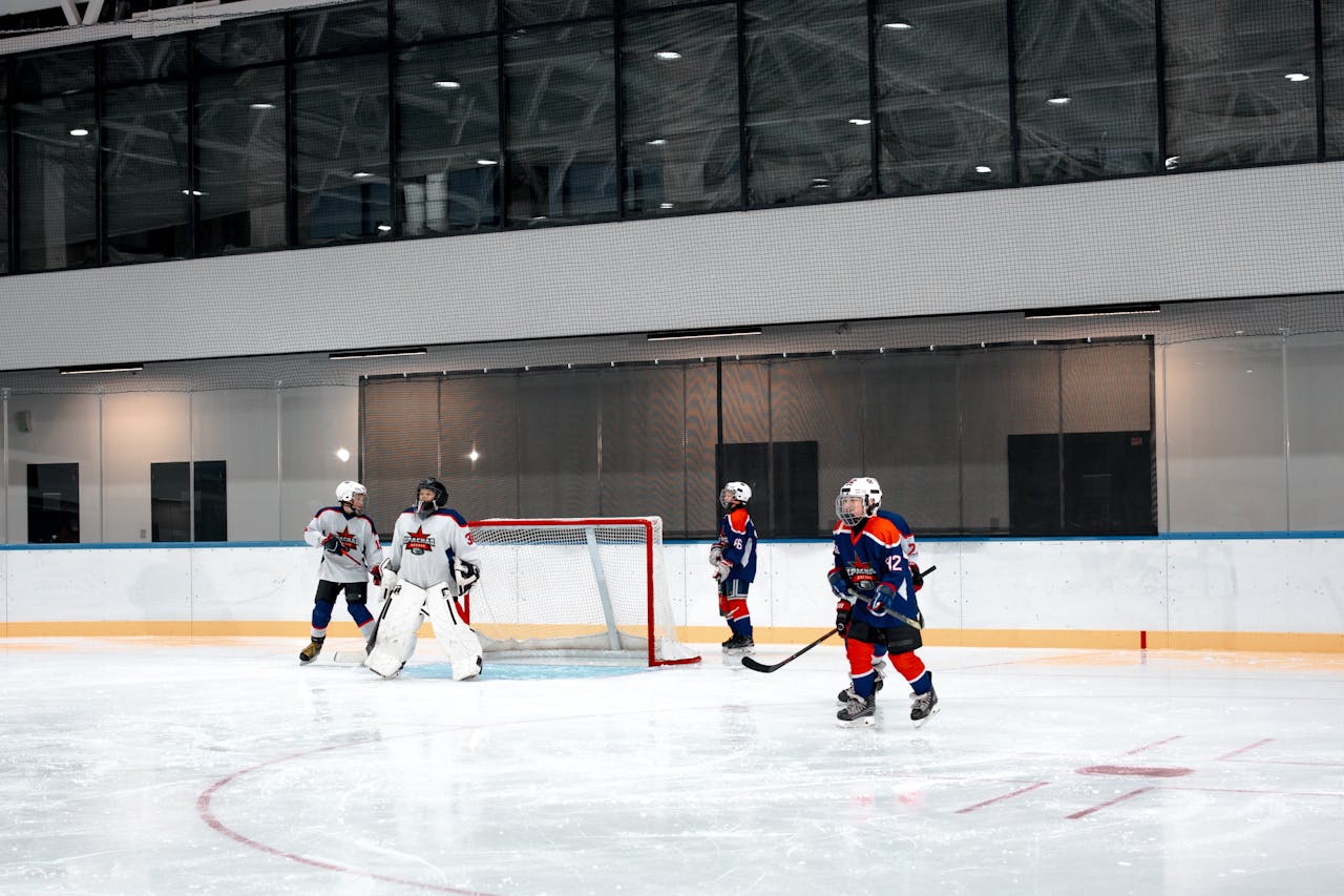 Young players compete in an indoor ice hockey match, showcasing teamwork and sportsmanship.
